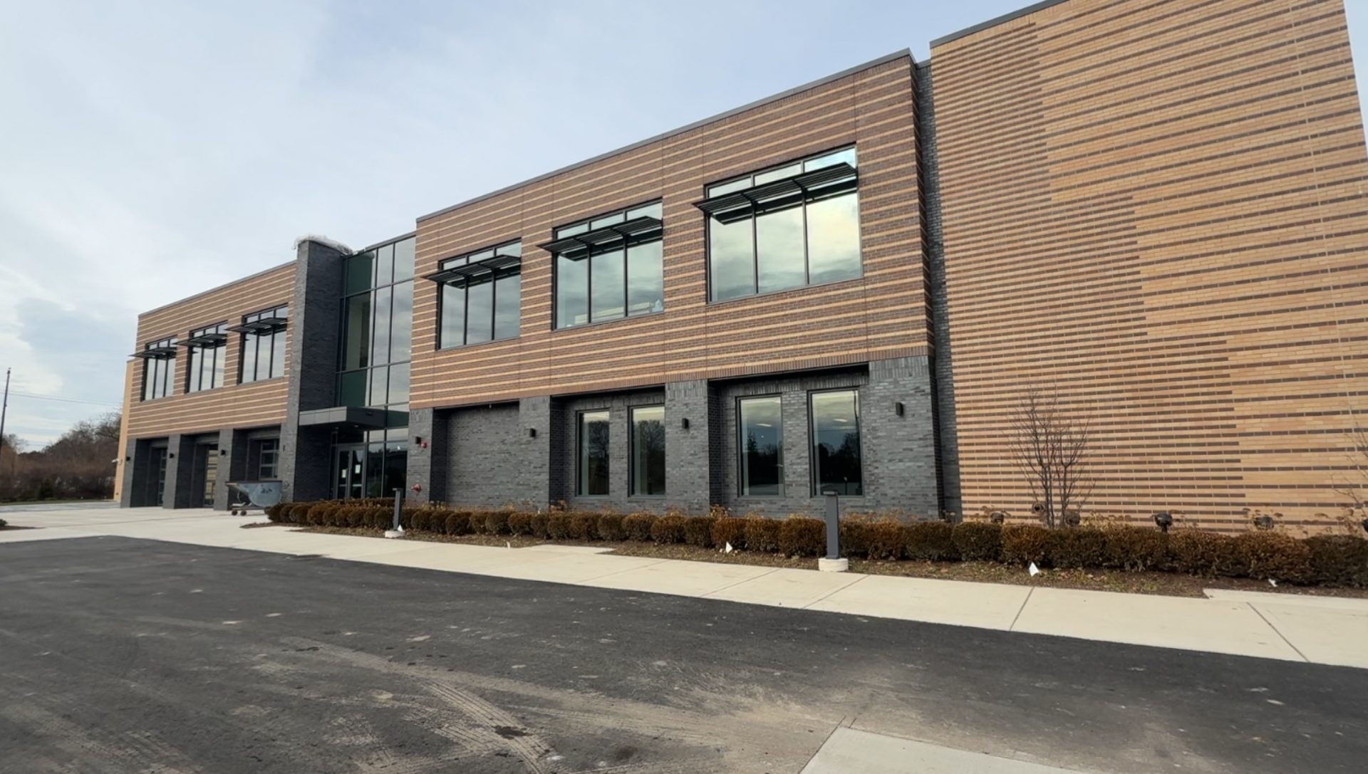 Two-story wing of the Redford Recreation & Wellness Center showing Kawneer Versoleil sunshades over storefront windows in a charcoal finish