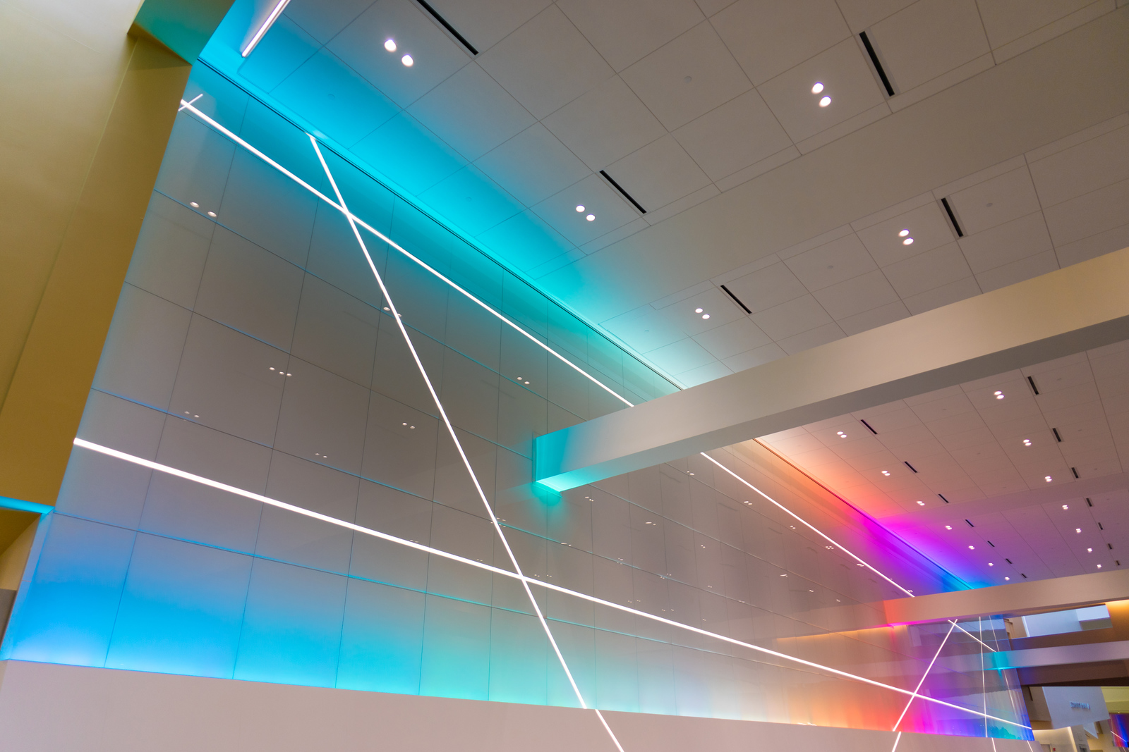 Back painted glass node wall LED light lines White back painted glass panels with diagonal LED light strips and a blue to green backlight at the Columbus Convention Center node wall