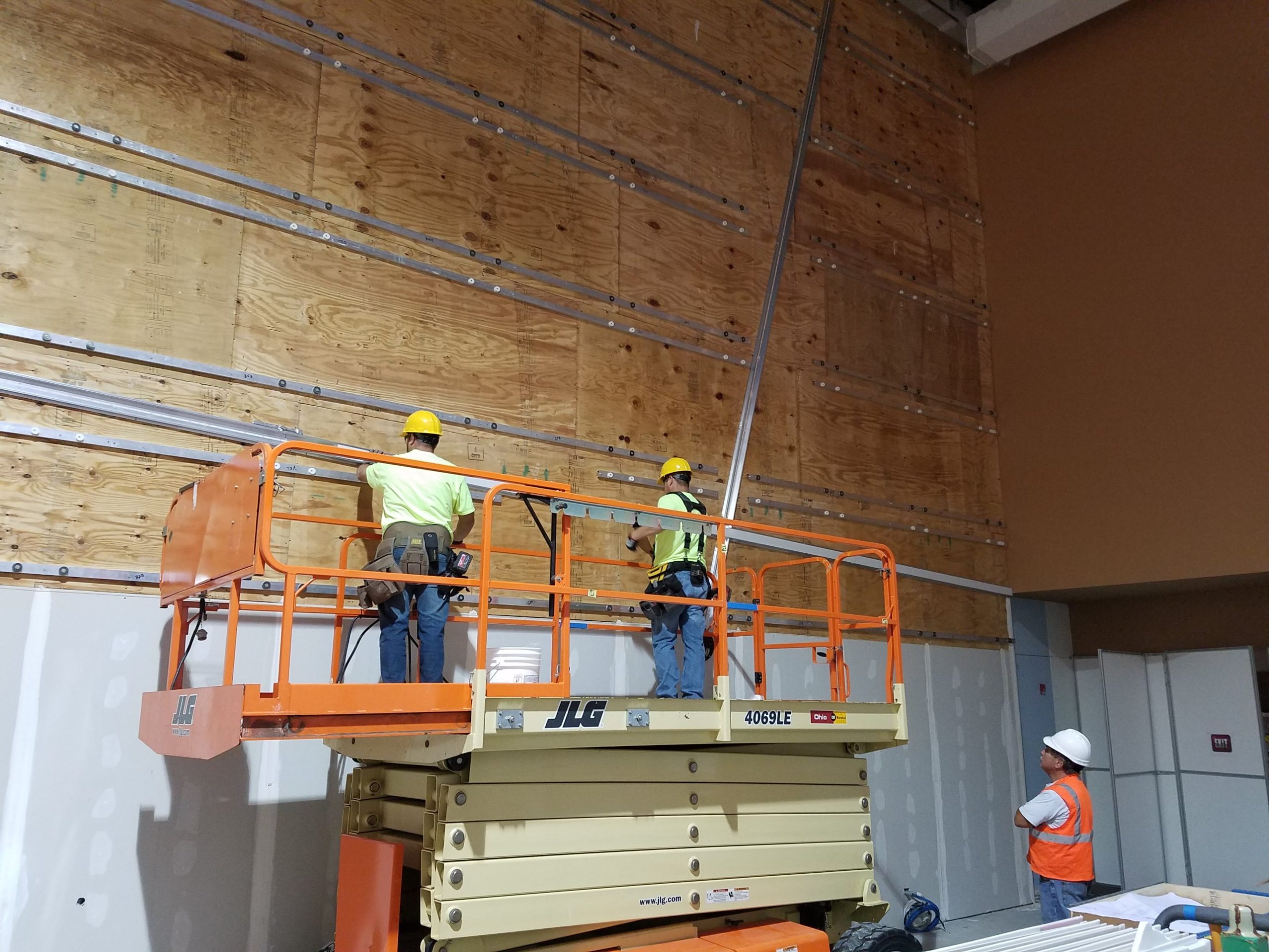 Node wall channels on plywood Aluminum hanging channels screwed to the plywood backing of a Columbus Convention Center node wall before the back painted glass goes up