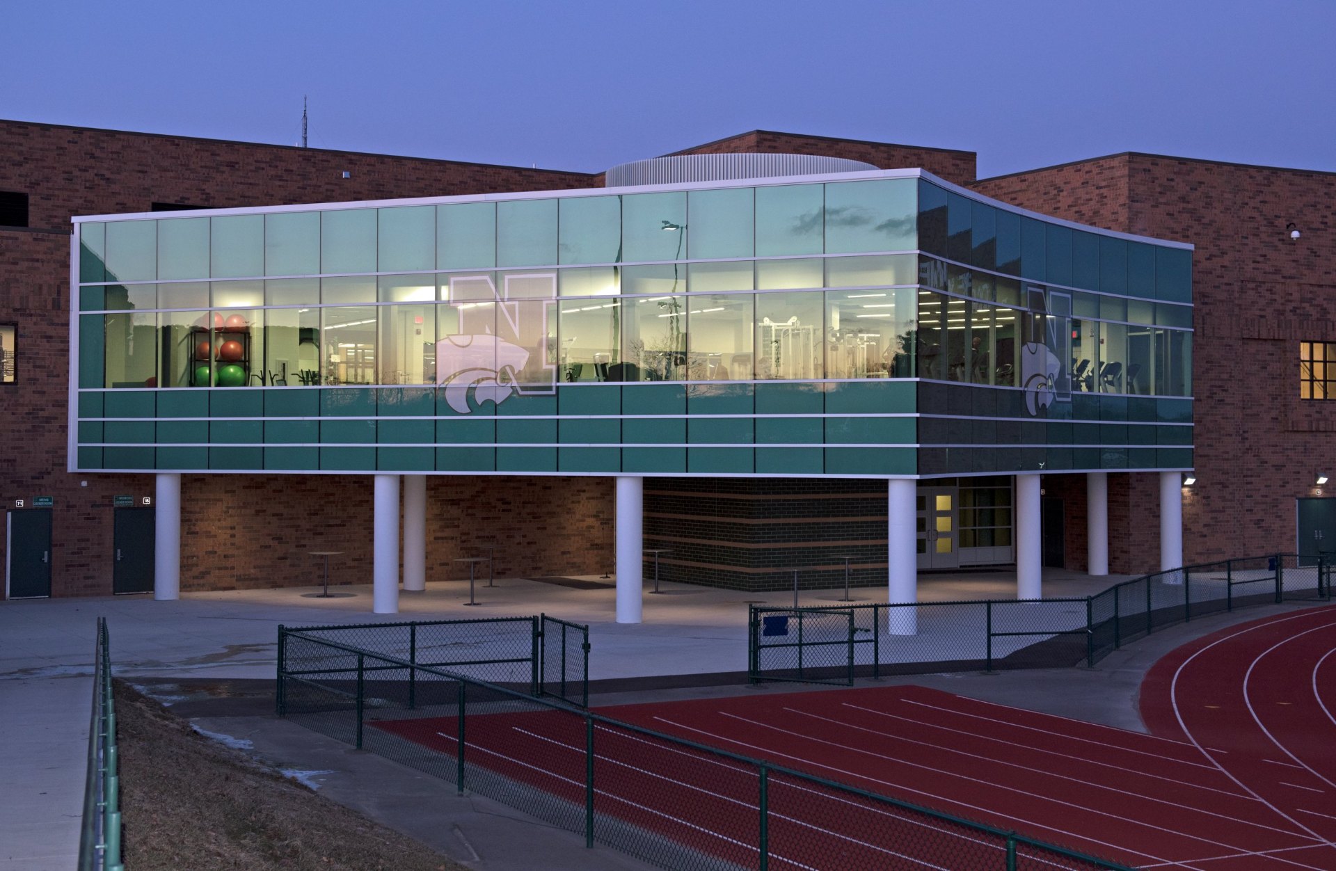 Novi High School fitness center at dusk, curved Tubelite curtain wall on cantilevered clips with curtain wall anchors to steel and no sill wall